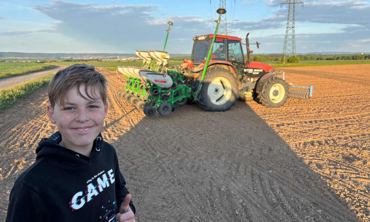 Jakob Rossnagl macht ein Selfie vor einem Traktor am Feld.